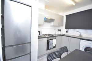 a kitchen with white cabinets and a sink and a dishwasher at London zone2 Classic 3 bedroom in London