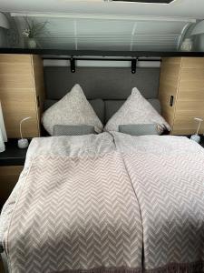 a bedroom with a large bed with two pillows at Luxuswohnwagen Dreamer mit Achterwasserblick in Lütow