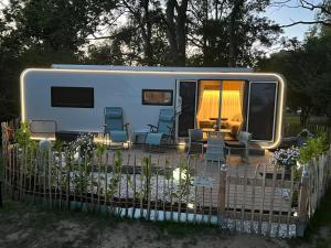 a white rv with chairs and a fence at Luxuswohnwagen Dreamer mit Achterwasserblick in Lütow
