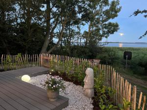 a garden with a wooden deck and a fence at Luxuswohnwagen Dreamer mit Achterwasserblick in Lütow