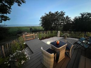 a patio with a table and chairs on a wooden deck at Luxuswohnwagen Dreamer mit Achterwasserblick in Lütow