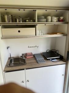eine Küche mit Spüle und einem Regal mit Geschirr in der Unterkunft Wohnwagen Beachy direkt am Achterwasser in Lütow