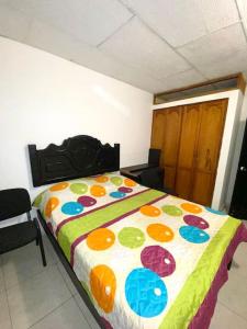 1 dormitorio con 1 cama con un edredón colorido en 2023 Apartamentos Múltiples Segundo Piso Casa Independiente, en Santa Marta
