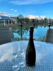 a bottle of wine sitting on a table with two glasses at Luxurious Lakefront Home with Pool/Spa Access in Cirencester