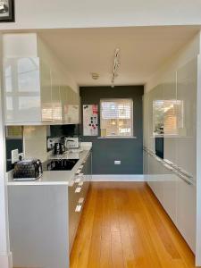 a kitchen with white cabinets and a wooden floor at Luxurious Lakefront Home with Pool/Spa Access in Cirencester