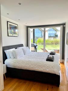 a bedroom with a large bed and a large window at Luxurious Lakefront Home with Pool/Spa Access in Cirencester