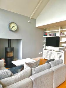 a living room with a couch and a clock on the wall at Luxurious Lakefront Home with Pool/Spa Access in Cirencester