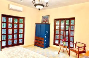 a bedroom with a blue cabinet and a chair and windows at Gardenhotel Macan Ché B&B in Izamal