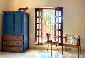 a room with a blue cabinet and a chair and a window at Gardenhotel Macan Ché B&B in Izamal