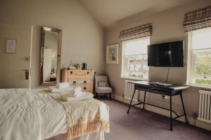 a bedroom with a bed and a desk and a television at Plum and Partridge Husthwaite in York