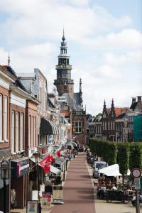 eine Straße in einer Stadt mit einem Uhrturm in der Unterkunft Hotel de Wijnberg in Bolsward