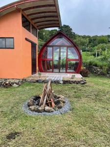 a fire pit in the grass in front of a house at Glamping Campo Alegre in Cartago