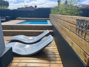- une piscine avec une chaise blanche à côté d'une terrasse en bois dans l'établissement 28 on Symonds Luxstudio 2 with solar backup, à George
