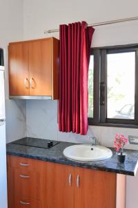 a bathroom with a sink and a red curtain at Guest House Gerard in Ksamil