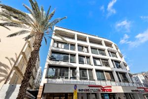 a tall white building with a palm tree in front of it at Renovated apt on Frishman beach with Bomb Shelter M8 in Tel Aviv