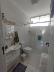 a white bathroom with a toilet and a sink at Apartamento Central, oitavo andar in Serra Negra