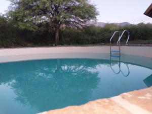 una piscina con una silla azul en el agua en Atardecida en Villa Las Rosas