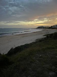 een strand bij zonsondergang met mensen die op het zand lopen bij RyQ-C in Jeffreys Bay