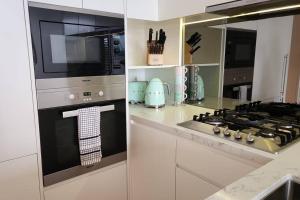 a kitchen with a stove and a microwave at Stay and Sea! in Sydney