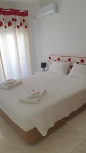 een groot wit bed met twee handdoeken erop bij Quarteira Beach in Quarteira