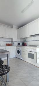 een keuken met witte kasten en een wasmachine bij Quarteira Beach in Quarteira