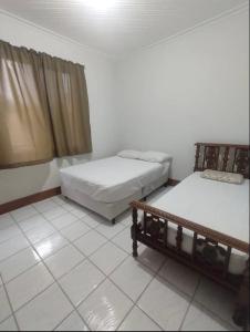 a room with two beds and a tiled floor at Casa no Centro de Serra Negra in Serra Negra