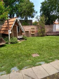 una pequeña casa en un patio con césped y una casa en Hostel Monte Grande en Monte Grande