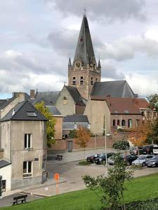 una iglesia con una torre de reloj y un aparcamiento en HUIS1874, en Geraardsbergen