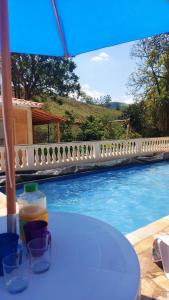 uma mesa com copos ao lado de uma piscina em Recanto Águas Claras em Soledade de Minas