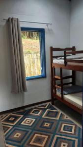 a room with a bed and a window and a rug at Recanto Águas Claras in Soledade de Minas