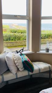 a bench with pillows sitting in front of a window at Port Pour Deux in Portrush
