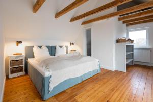 um quarto com uma cama grande e piso em madeira em Deichkind 25 em Hedwigenkoog