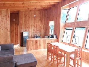 sala de estar con paredes de madera, mesa y sillas en Cabañas piedra Alta, Huilo Huilo, en Panguipulli