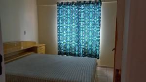 1 dormitorio con cama y cortina azul en Apto completo no centro 2qtos - Residencial Ponta Verde., en Caldas Novas