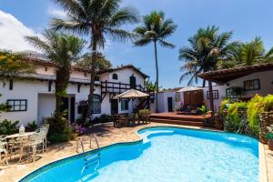 a villa with a swimming pool and palm trees at Casa Aldeia Paraty in Paraty