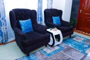 two chairs and a side table in a living room at The porch garden Estate 1 bedrm in Nairobi