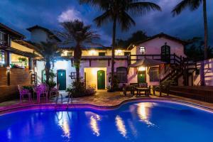 a swimming pool in front of a house at night at Casa Aldeia Paraty in Paraty
