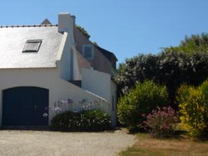 a white house with a garage and some flowers at Appartement Le Palais, 2 pièces, 2 personnes - FR-1-418-165 in Le Palais