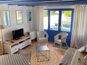 a living room with a couch and a tv and chairs at Maison Locmaria, 2 pièces, 4 personnes - FR-1-418-163 in Locmaria