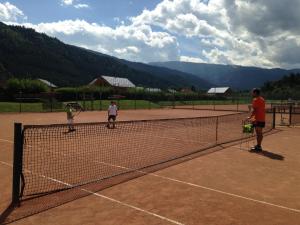 three people playing tennis on a tennis court at Wellness Chalet Bell a Mur in Murau