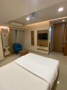 a bedroom with a large white bed and a tv at Greens Suite - Business Class Hotel - Opposite Ripon Building in Chennai