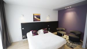 a bedroom with a white bed and two chairs at Logis Hôtel Relais de Vincey in Vincey