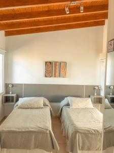 two beds in a room with white walls and wooden ceilings at Good Life Resort in La Falda