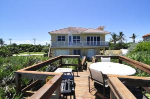een terras met een tafel en stoelen en een huis bij Pelican Perch-Four bedroom heated pool oceanfront home in Melbourne Beach