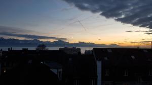 um pôr-do-sol sobre os telhados de edifícios de uma cidade em Beauregard attique em Lausanne