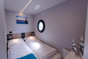 Hausboot Fjord Lacerta mit Dachterrasse in Wendtorf في Wendtorf: غرفة نوم بسرير وساعة على الحائط