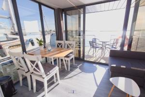 ein Esszimmer mit Tisch und Stühlen und Fenstern in der Unterkunft Hausboot Fjord Lacerta mit Dachterrasse in Wendtorf in Wendtorf