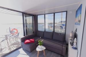 a living room with a couch and a view of the ocean at Hausboot Fjord Lacerta mit Dachterrasse in Wendtorf in Wendtorf