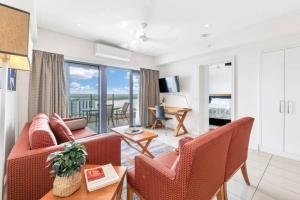 uma sala de estar com um sofá, cadeiras e uma mesa em Luxury two-beds harbour views apartment em Darwin