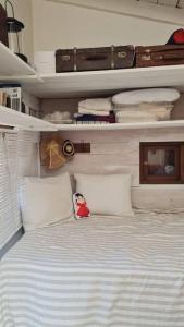 1 dormitorio con 1 cama con almohadas blancas y equipaje en Tiny house y casa Parador de playa, en La Pedrera